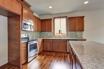 Modern kitchen room with brown cabinets, granite counter tops and hardwood floor.