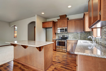 Kitchen room interior with brown cabinets, kitchen island, granite counter tops.