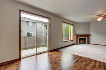 Large empty living room interior with carpet floor and fireplace.