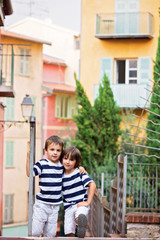 Two sweet children, boy brothers, standing on stairs, hugging ea