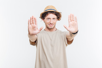 Young man in a hat showing stop gesture