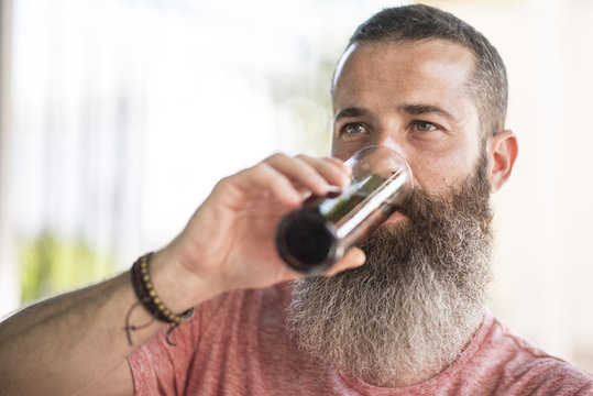 Bearded hipster drinking cold beverage from glass