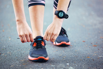 Close up of young woman tying her laces before a run.