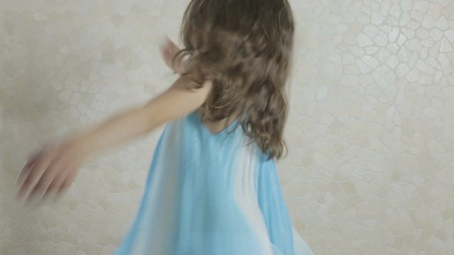 Beautiful girl in blue dress spinning happily.