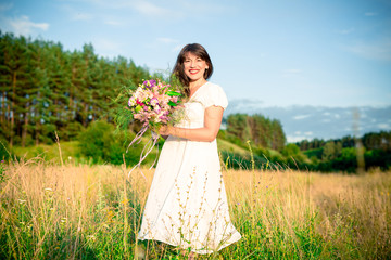 young woman with a bouquet in hand spinning and dancing in the forest and fields