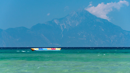 Inflatable banana shaped boat at sunset on a calm sea, Mount Athos in the background
