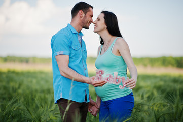 Happy pregnant couple on wreath field in love