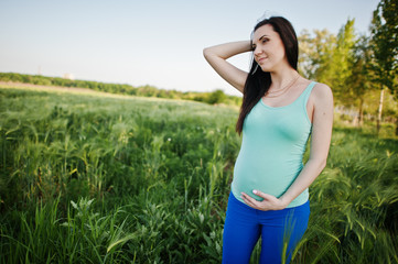 Naklejka na ściany i meble Beautiful brunette pregnant woman at wreath field