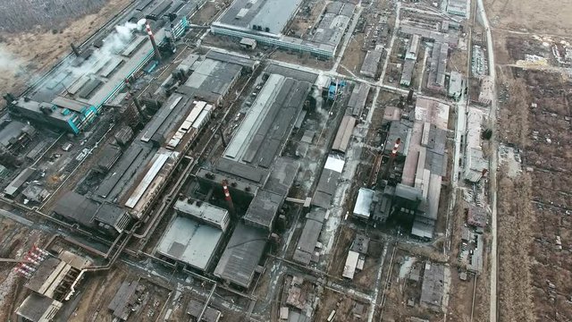 Aerial view of large industrial plant consisting of various buildings and constructions with smoking chimneys polluting air 