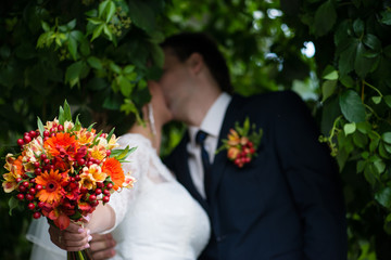 blur background with wedding bouquet and newlyweds kiss, shallow