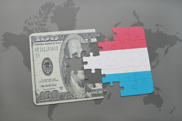puzzle with the national flag of luxembourg and dollar banknote on a world map background.