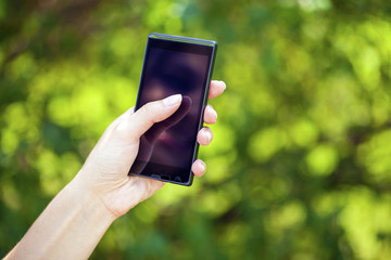 Side view of a woman's hand holding a modern slick smartphone