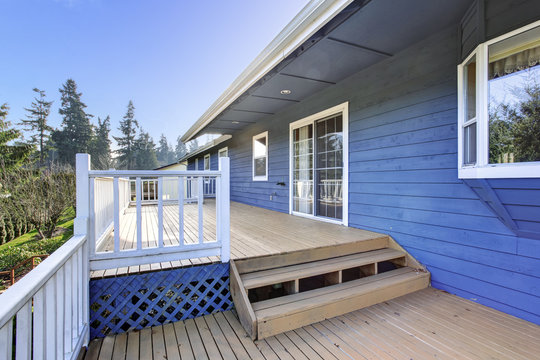 View of wooden walkout deck with white railings and stairs.