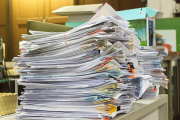 Stack of files full of documents signifying concepts such as work and stress, and business objects.