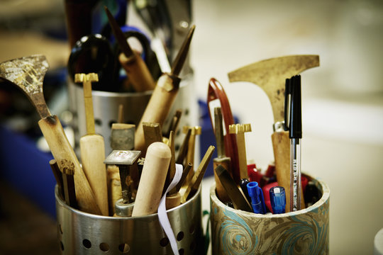 Metal pots full of hand tools for skilled work, for book binding tasks. 