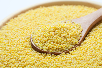 Fresh organic millet with spoon in wooden bowl, Close-up.