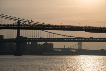 Dark silhouettes of sections of Brooklyn, Manhattan and Willamsburg bridge at dawn