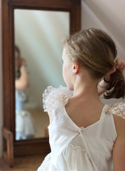 Little girl dresses up in front of the mirror.