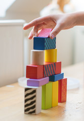 Child hand playing with toy blocks.