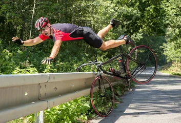 Rolgordijnen Fietser valt van de fiets in struiken. Ongeval met fiets op de weg. © milkovasa