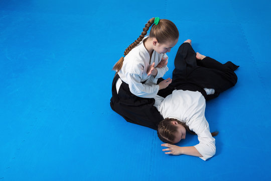 Two girls in black hakama practice Aikido on martial arts training