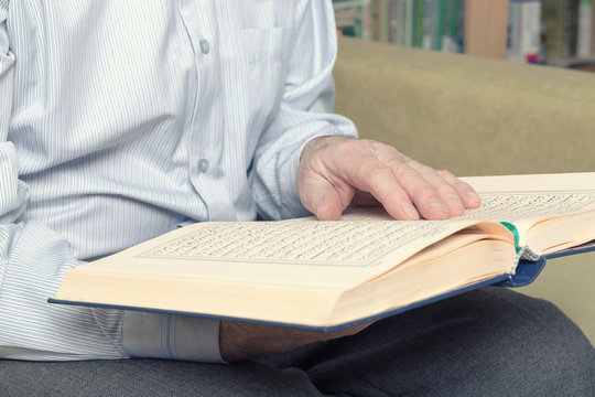 An old man hands holding the Koran. Selective focus