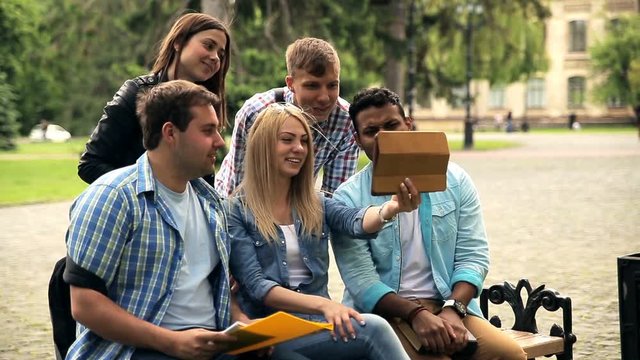 Group of students saying hi to friend using tablet