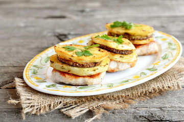 Fried Turkey fillet with potatoes, zucchini and parsley on a plate and on a burlap. Meat with vegetables on a wooden table. Delicious lunch or dinner recipe. Closeup