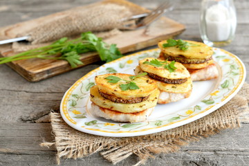 Roasted Turkey steak with potatoes, zucchini and parsley on a plate and on a burlap. Fork and knife on a chopping board, fresh parsley, salt shaker on old wooden table. Holiday food idea