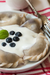 Vareniki. Dumplings with blueberries. Served with sour cream. Dish of Russian and Ukrainian cuisine. Selective focus

