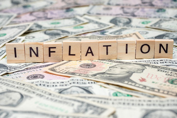 Word "Inflation" in wooden block on US Dollar bills