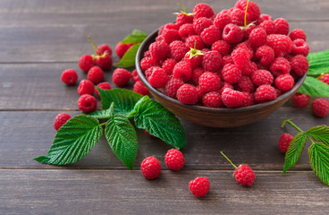 Red fresh raspberries on brown rustic wood background