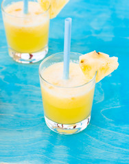 two glasses of fresh orange juice with blue straw on a blue background
