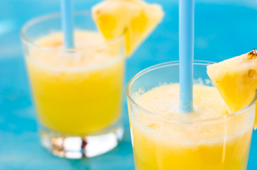two glasses of fresh orange juice with blue straw on a blue background