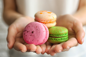 Female hands holding tasty macaroons, close up