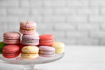 Colorful tasty macaroons in glass stand on blurred brick wall background