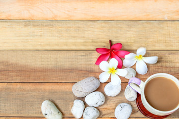 Fototapeta na wymiar coffee cup with Plumeria flower and stone on wood plate