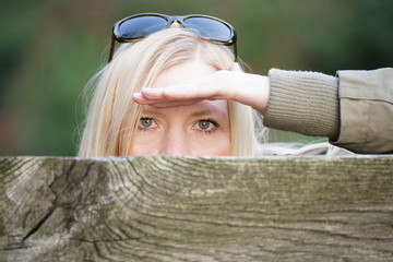 Frau beobachtet versteckt über Zaun