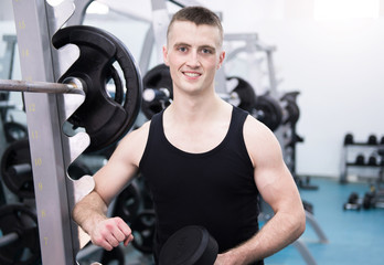 Fototapeta na wymiar Athletic man with a dumbells in gym