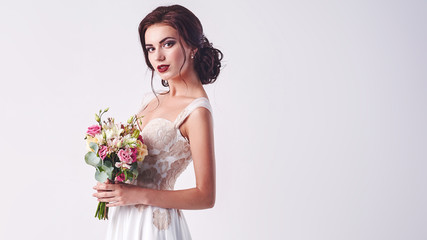 Young attractive bride with the bouquet of white roses
