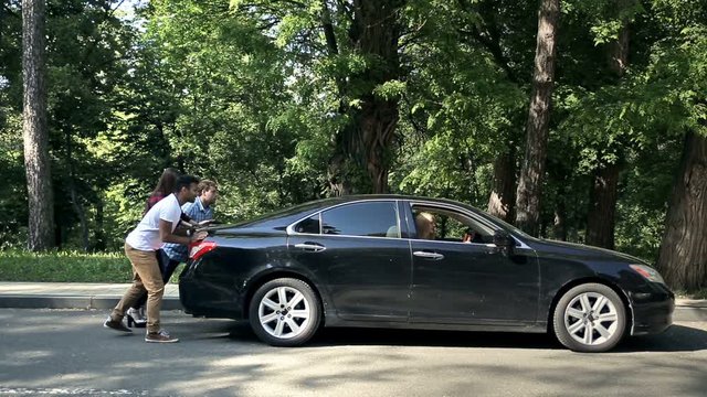 Men Helping Charming Women To Push Car On Road