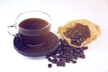  grains of coffee plant and black coffee drink on white wood bac