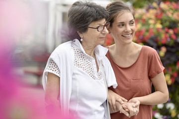Home carer helping disabled woman walking with crutch