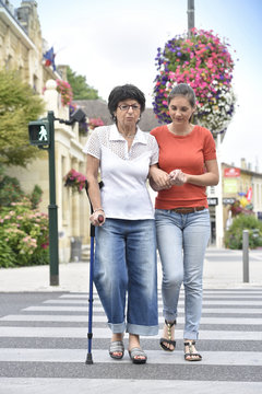 Home carer helping senior woman crossing the street