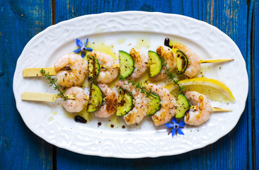 Shrimps skewers with zucchini on wooden background