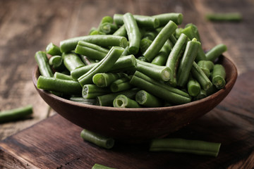 Bunch of freshly picked green beans on a wooden surface.