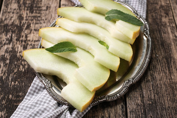 Fresh melons sliced and mint on wooden table, healthy food