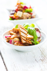 Delicious salad with grilled chicken breast on a wooden background