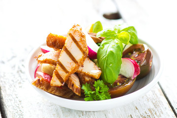 Delicious salad with grilled chicken breast on a wooden background