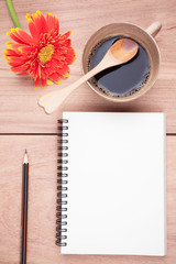 Gerbera flower,coffee, notebook and pencil on the wood table